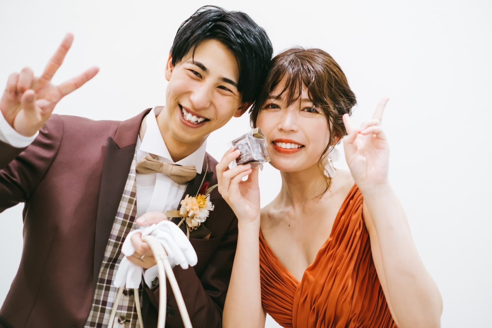 赤茶色のスーツの新郎とオレンジ色のドレスの花嫁のお写真
