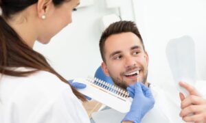 女性の歯科従事者に歯の色を測ってもらっている男性の画像