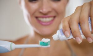 歯ブラシに歯磨き粉を絞り出している女性の画像
