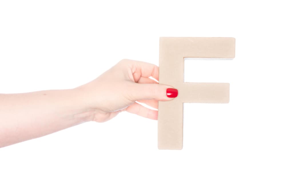 「F」の茶色いブロックを持った女性の手の画像