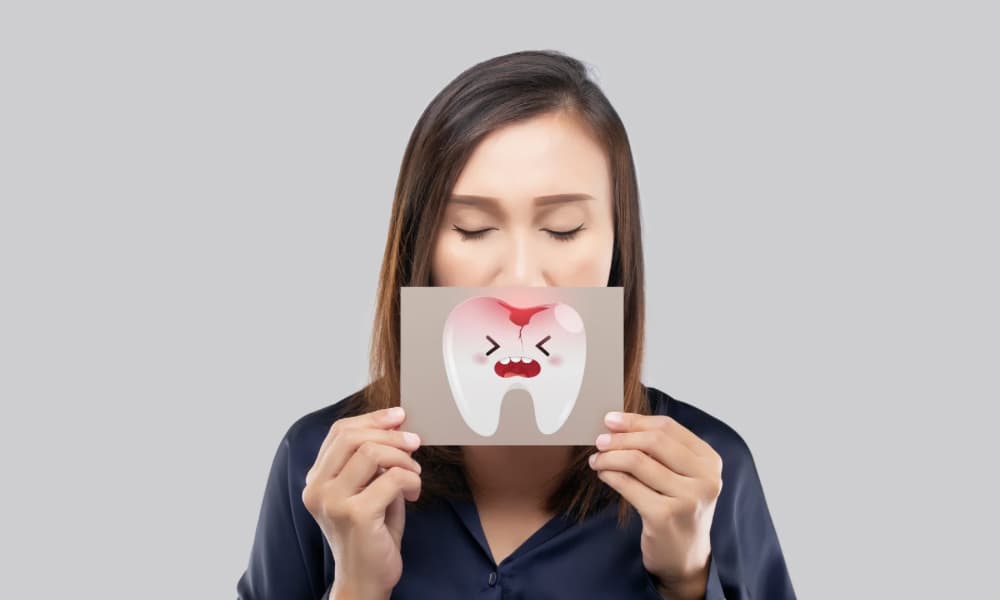 炎症が起こっている歯のイラストを口元に当てている女性の画像