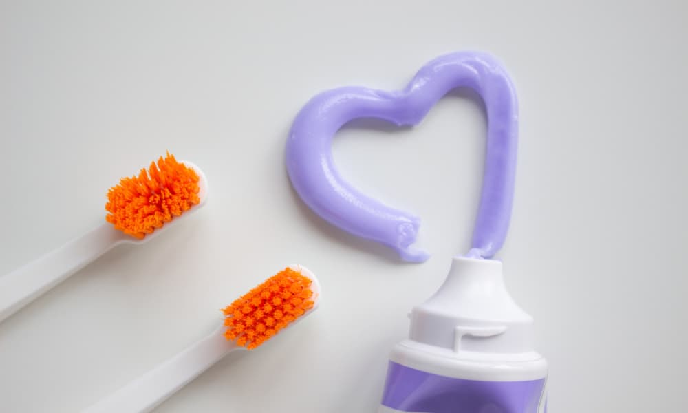 ハート型の紫色の歯磨き粉とオレンジ色の歯ブラシが写っている画像