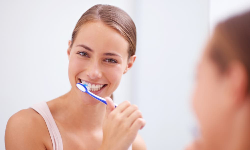 女性が笑顔で歯磨きをしている画像