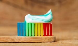 赤、黄、緑、青の毛先をした歯ブラシの上に歯磨き粉が乗っている画像