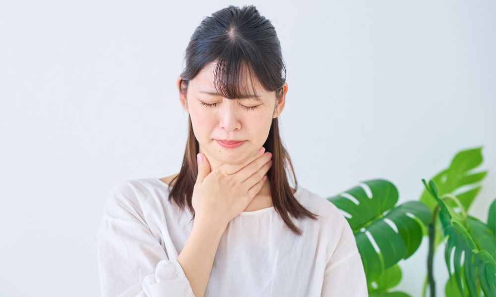 のどに違和感を感じている若い女性