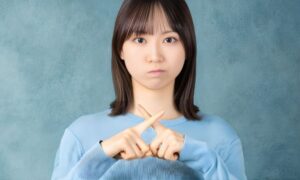 手でバッテンをしている若い女性