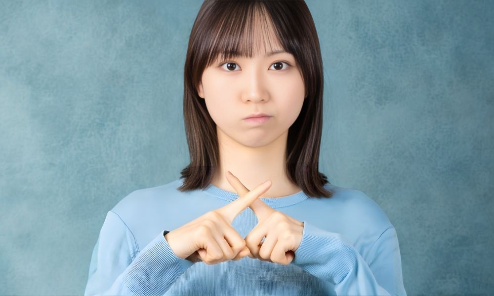 手でバッテンをしている若い女性