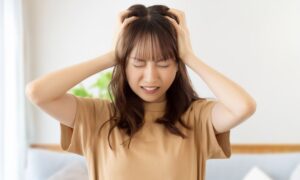 頭を抱えて悩んでいる若い女性